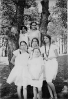 [Trzy siostry Stanisława Bereźnicka, Halina Bereźnicka, Bronisława Bereźnicka w towarzystwie panien stojących w parku przy drzewie]