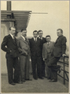 Czesław Bartkowiak wśród mężczyzn przy budynku